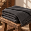 Charcoal pashmina lohi folded on a rustic wooden stool