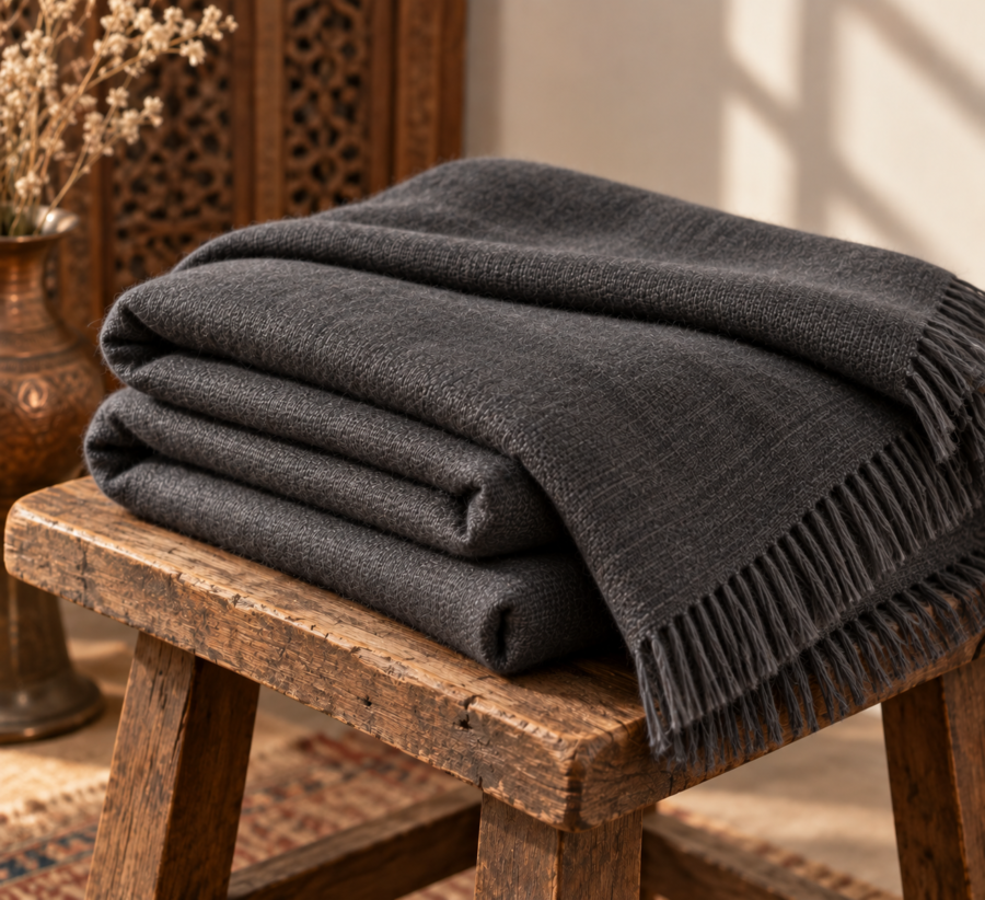 Charcoal pashmina lohi folded on a rustic wooden stool